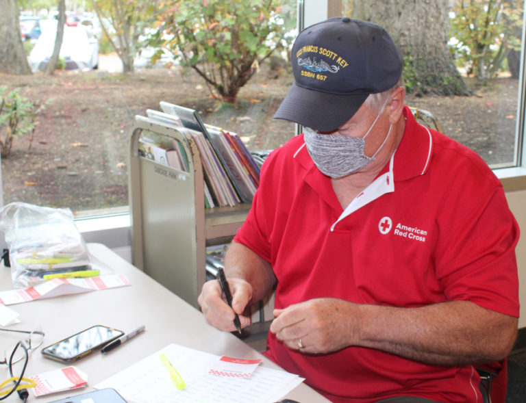Washougal veteran Keith Mills wears his USS Francis Scott Key naval hat while helping sign people into an American Red Cross blood donation event at the Cascade Park Community Library in Vancouver, on Oct.