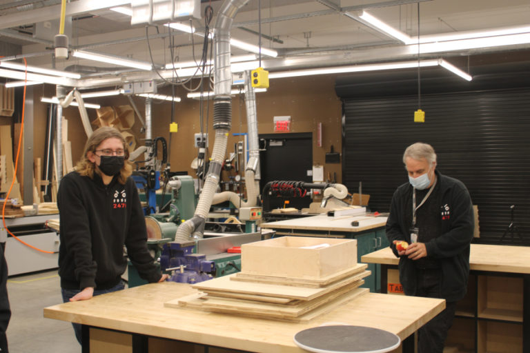 Washougal High School senior Zach Ager (left) and Discovery High School teacher Bruce Whitefield (right) discuss a new home health care device created by Camas-Washougal students inside Discovery High's STEM lab on Wednesday, Dec. 1, 2021.