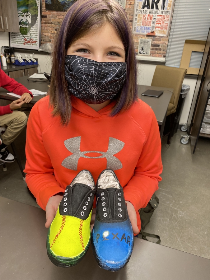 Above: Jemtegaard Middle School student Aubrey Timmons holds the shoes she made during a &quot;Roots and Wings&quot; art project in December 2021. Below: A pair of shoes created by a Washougal middle-schooler during a &quot;Roots and Wings&quot; art project in December 2021.