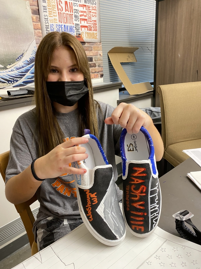 Jemtegaard Middle School student Ellie Sneer holds shoes she designed for an art project in December 2021.
