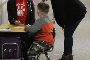 Hathaway Elementary School principal Wendy Morrill (right) and Read Northwest volunteer Jessica Hooper (left) talk to first-grade Hathaway student Kilian Libbett (center) during a "reading buddy" session on Friday, March 11, 2022. (Doug Flanagan/Post-Record)