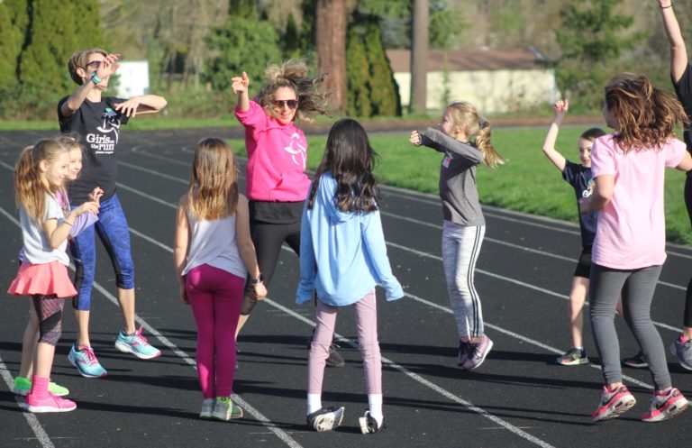 Doug Flanagan/Post-Record 
 Washougal Girls on the Run coach Lilia Grundy (pink shirt) leads her team in a celebratory  activity during a practice session on Thursday, March 24, at Columbia River Gorge Elementary School.