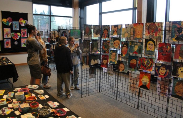 Doug Flanagan/Post-Record 
 Canyon Creek Middle School art teacher Alice Yang (second from left) shows student artwork to attendees during the 2022 Washougal Youth Arts Month gallery exhibit on Wednesday, March 23, at Washougal High School.