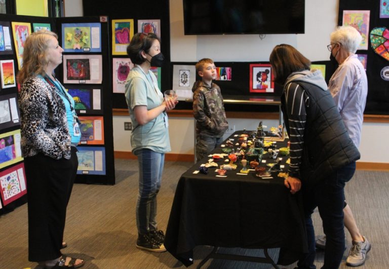Doug Flanagan/Post-Record 
 Columbia River Gorge Elementary School art teacher Jessica Blumer (left) shows student artwork to attendees during the 2022 Washougal Youth Arts Month gallery exhibit on Wednesday, March 23, at Washougal High School.