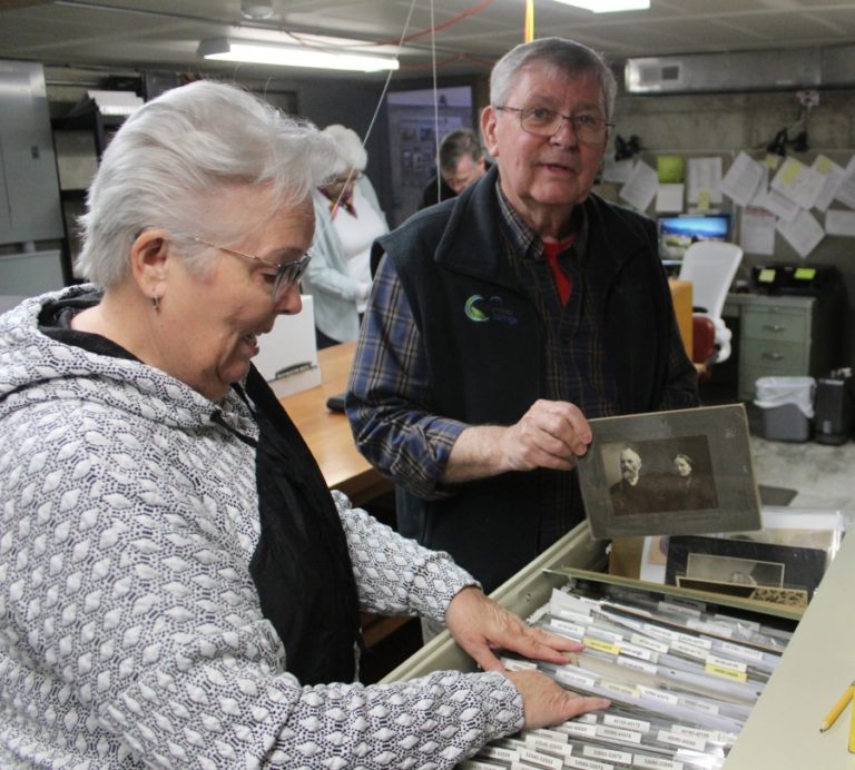Camas-Washougal Historical Society board member Richard Johnson (right) holds a  vintage photograph while his wife, Karen Johnson (left), flips through file folders filled with old images at Two Rivers Heritage Museum in Washougal on Thursday, March 31, 2022.
