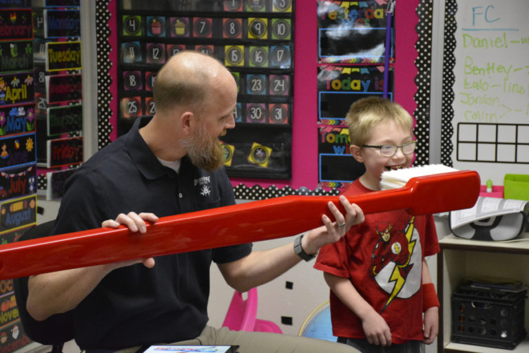 Dave Stinchfield, a dentist at Discovery Dental in Washougal, shows student Gracin Hobensack how to use a giant toothbrush at Hathaway Elementary School in March 2018.
