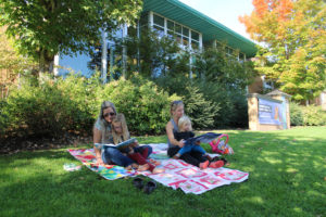 Cheryl Markwood, of Michigan (left), Janice Cole, of Camas (right), and Cole’s children, 5-year-old Zoe (on Markwood’s lap) and 2-year-old Henry (on Cole’s lap) read books outside the Camas Public Library on Oct. 9, 2020. (Kelly Moyer/Post-Record files)
