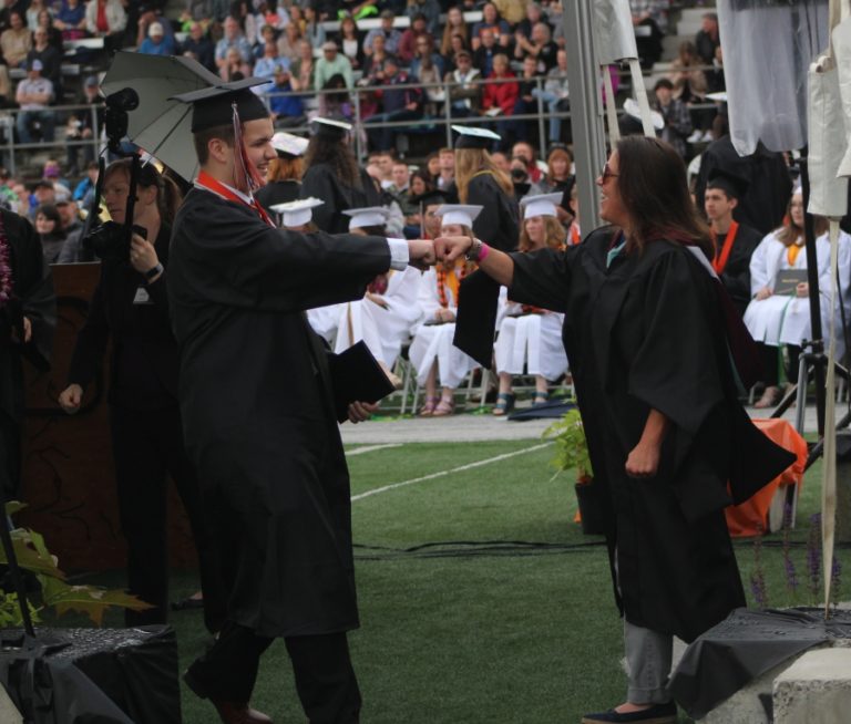 Doug Flanagan/Post-Record 
 Washougal High School teacher Heather Carver (right) fits-bumps a graduate during the Washougal High School class of 2022 commencement ceremony at Fishback Stadium on Saturday, June 11.