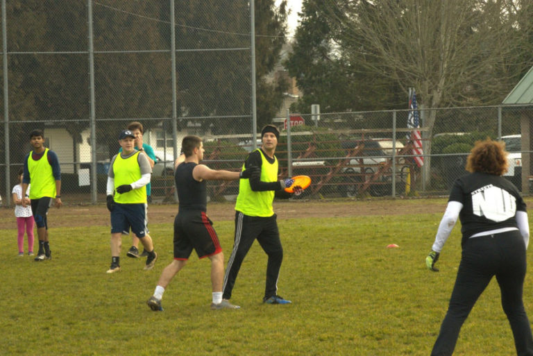 Members of the Goot Times Ultimate team, including Brandon Zarzana (center, holding disc) and Derek Lawton (third from left, guarding Zarzana), play Ultimate Frisbee at Camas&#039; Goot Park in 2022.