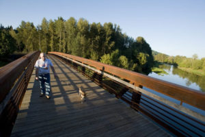 A hiker and their dog walk along the Washougal River Greenway trail in Camas. (Contributed photo courtesy of The Columbian)