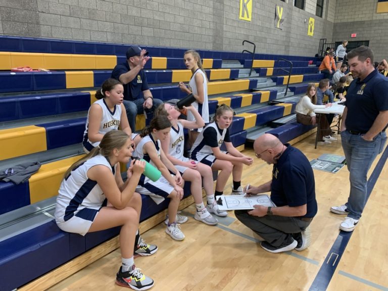 Jemtegaard Middle School girls basketball coach Eric Johnson (second from right) talks to his team during a game in late 2022.