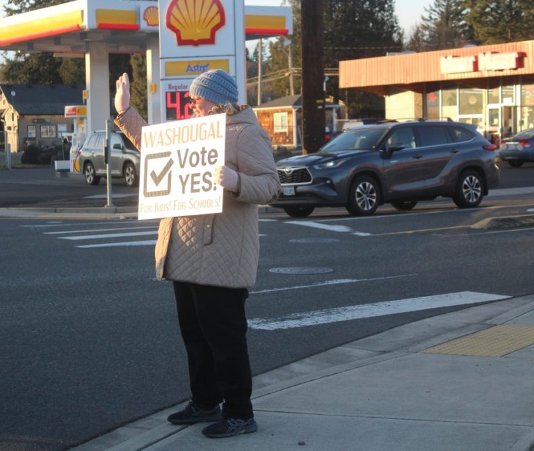 Washougal resident Nichol Yung waves to a passing vehicle while holding a &quot;Vote Yes&quot; sign at the northeast corner of 32nd Street and Evergreen Way in Washougal on Jan.