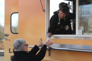 Washougal School District career and technical education assistant Alex Yost (right) hands a bowl of chili to an event attendee at Washougal High School's ribbon-cutting ceremony celebrating the opening of the district's Shoug Shack food-truck business, on Thursday, Feb. 2, 2023. (Doug Flanagan/Post-Record)