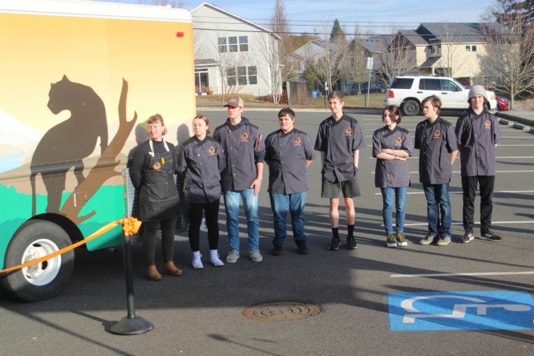 Doug Flanagan/Post-Record 
 Washougal School District career and technical education assistant Alex Yost (far left) and culinary arts students listen to a speech on Thursday, Feb. 2, during a ribbon-cutting ceremony celebrating the opening of the district&#039;s Shoug Shack food-truck business.