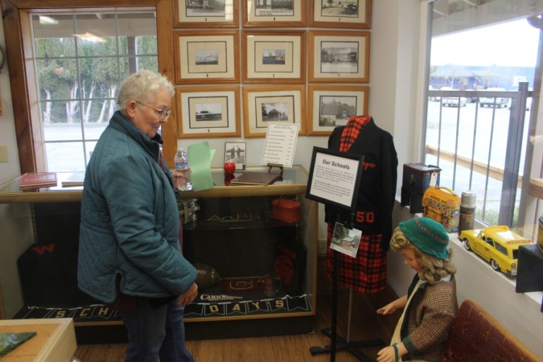 A Two Rivers Heritage Museum volunteer looks at the museum&#039;s collection of school memorabilia on Friday, Feb.