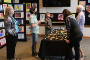Cape Horn-Skye Elementary and Canyon Creek Middle school art teacher Alice Yang (second from left) shows student artwork to attendees during the 2022 Washougal Youth Arts Month gallery exhibit on Wednesday, March 23, 2022, at Washougal High School. (Post-Record files) 