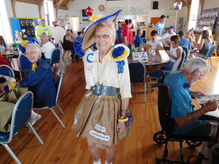 Camas historian Virginia Warren shows off her paper dress during the 2018 luncheon for current and former members of the Camas Days Royal Court in July 2018.