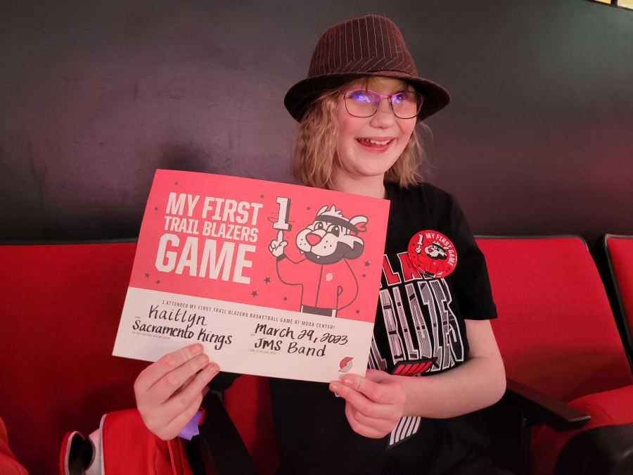 Jemtegaard Middle School music student Kaitlyn Gregersen holds a "My first Trail Blazers game" sign at the Moda Center on Wednesday, March 29, 2023.