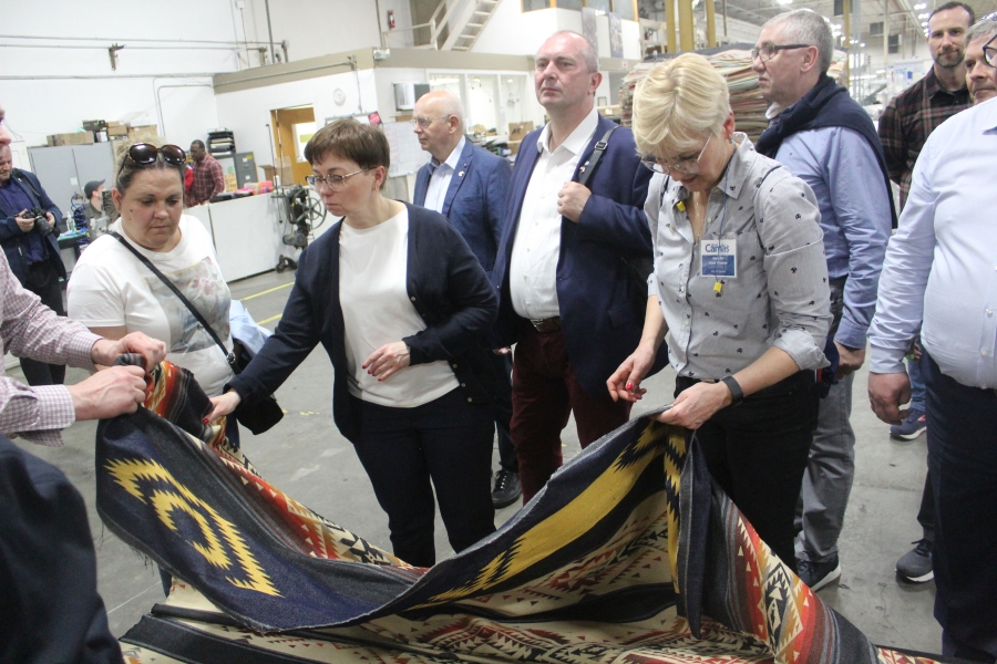 Roma Toft (right), of Zielonki, Poland, picks up a Pendleton blanket Wednesday, April 26, 2023, during a tour of the Pendleton Woolen Mill factory in Washougal. (Doug Flanagan/Post-Record)