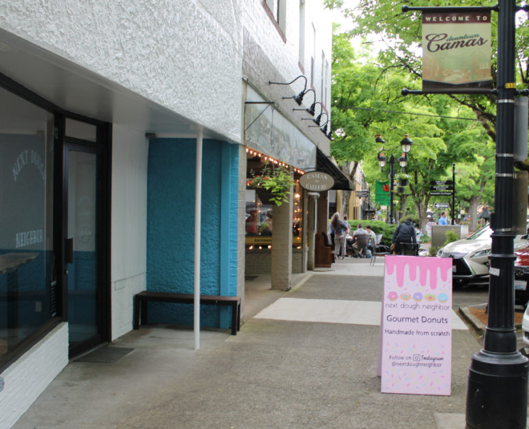 A sign advertises Next Dough Neighbor, a new doughnut shop that opened in April 2023 at 412 N.E.