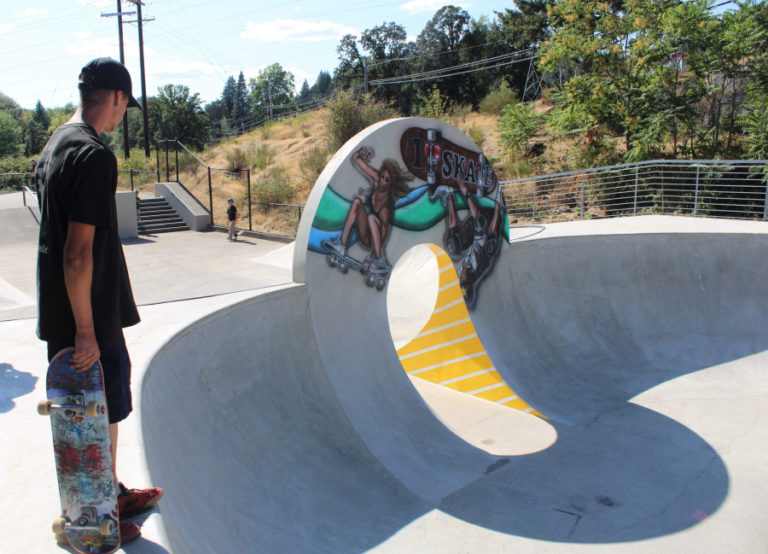 Skaters overlook a concrete bowl and mural by Washougal artist Kevin Seagraves (not pictured) Thursday, July 27, 2023, during a grand reopening event for Camas' Riverside Bowl Skatepark.