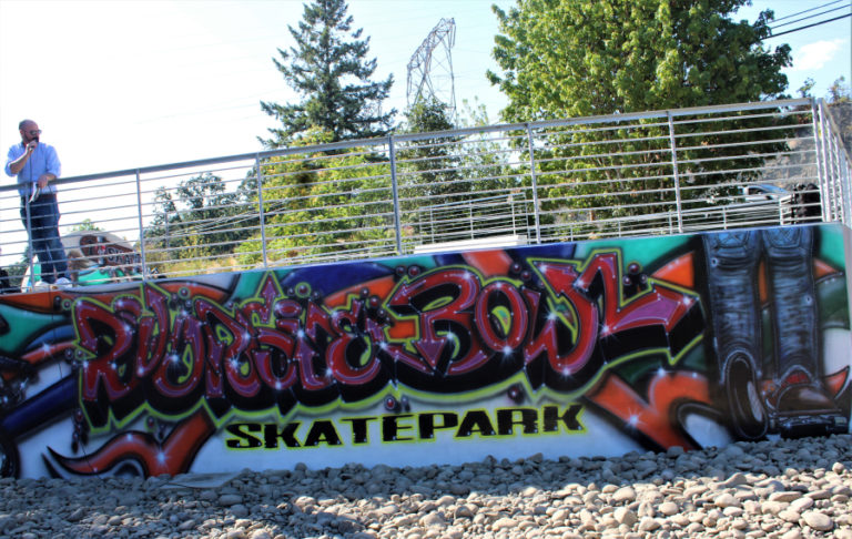 Camas Communications Director Bryan Rachal speaks Thursday, July 27, 2023, from a platform above a mural created by Washougal artist Kevin Seagraves, during the grand reopening of the newly remodeled Riverside Bowl Skatepark in Camas.