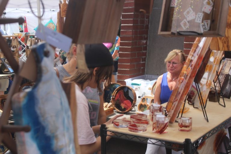 Michelle Wright (right) of Rushing River Design looks on as attendees browse her artwork during the 2023 Washougal Art Festival, held Saturday, Aug. 12, 2023, at Reflection Plaza in downtown Washougal.