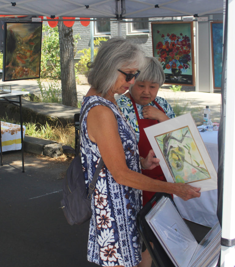 Artist Hiroko Stumpf (right) talks about her artwork with an attendee during the 2023 Washougal Art Festival, held Saturday, Aug. 12, 2023, at Reflection Plaza in downtown Washougal. (Photos by Doug Flanagan/Post-Record)