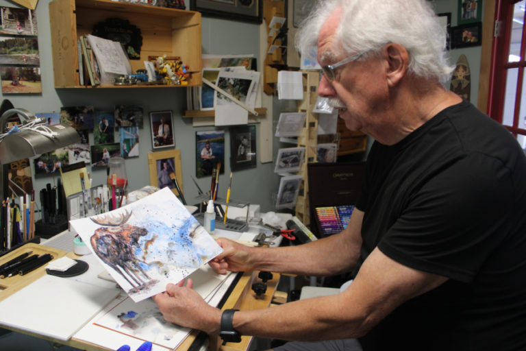 Gary Watson shows one of his recent wildlife-inspired paintings inside his art studio in east Clark County on Thursday, Aug. 17, 2023.