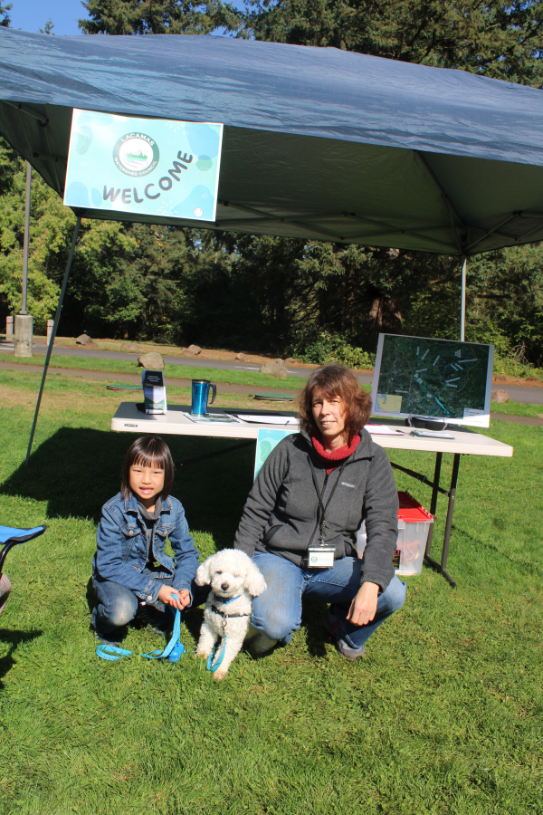 Judit Lorincz (right), the executive director of the Lacamas Watershed Council, and her 1-year-old dog, Charlie, greet 9-year-old Clara Tay, of Camas, during the 2023 Lacamas Lake cleanup and ivy pull event held Saturday, Sept.