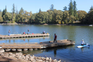 People gather on boat docks at Heritage Park in Camas ,and a kayaker paddles into Lacamas Lake Saturday, Sept. 30, 2023, following the annual Lacamas Lake cleanup event. (Photos by Kelly Moyer/Post-Record)