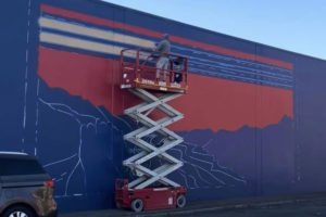 Washougal artist Travis London paints a mural on the north side of the Pendleton Woolen Mills building in Washougal in September. (Contributed photo courtesy Travis London)