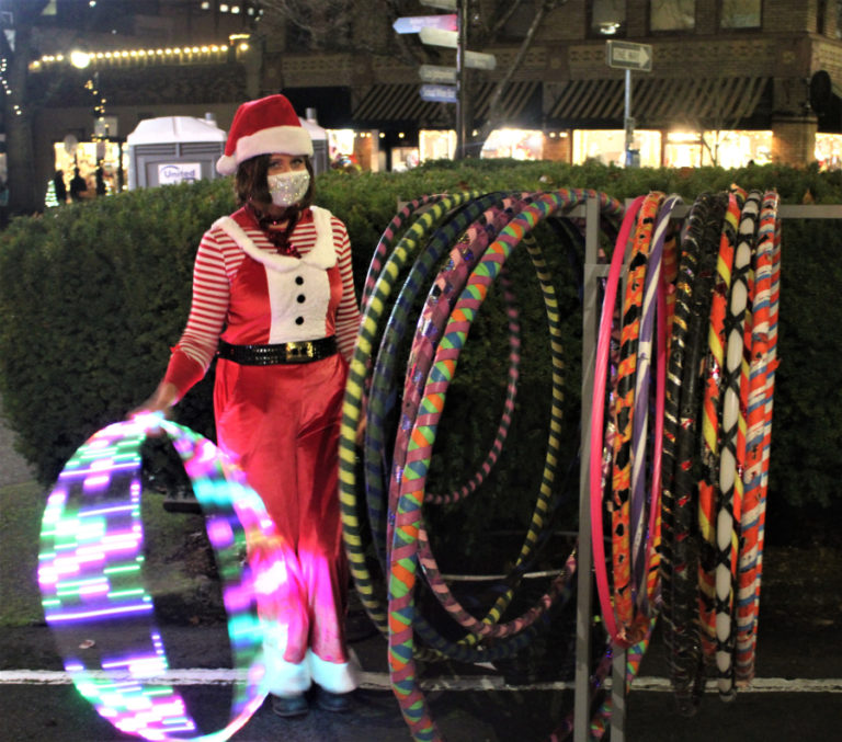 A volunteer offers hula hoops to families waiting in line to see Santa Claus during the 2021 Camas Hometown Holidays event.