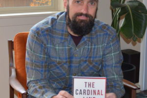 Jordan Fitch holds a copy of his debut novel, 