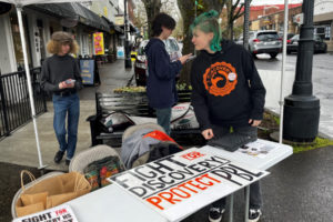 Discovery High School students (from left to right) Jax Goetzen, Angel Harp, Zimri Baxter and Hannah Cuffel-Leathers gather at a booth on the corner of Northeast Fourth Avenue and Northeast Cedar Street in downtown Camas during the Downtown Camas Association's First Friday event on April 7, 2023. The students are calling for the Camas School District to reconsider budget cuts that will impact their project-based learning high school. (Kelly Moyer/Post-Record)