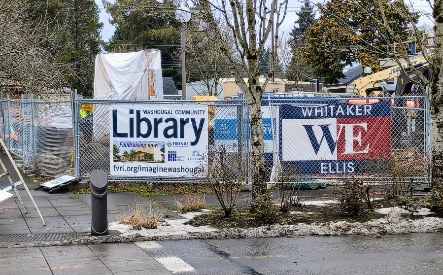 A sign attached to a fence surrounding a construction site for a mixed-use building at 1625 Main St., in downtown Washougal, touts fundraisng efforts for a new Washougal library, Monday, Jan. 22, 2024. The library will eventually sit next to the six-story mixed-use building.