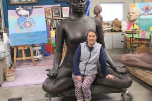 Yvonne Gee sits on a bronze sculpture created by her partner, Daviid Van Zandt, in their Washougal home studio, Friday, Jan. 26, 2024. (Doug Flanagan/Post-Record)