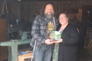 Washougal artists John and Anni Furniss hold a bowl they created together, with John doing the woodworking and Anni completing the painting, in their Washougal garage/studio, Thursday, Feb. 2, 2024. (Doug Flanagan/Post-Record)