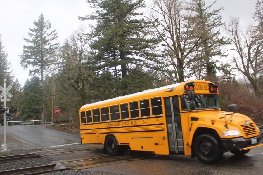 A school bus crosses the west railroad crossing into Skamania Landing, Tuesday, March 12, 2024. Residents say stopped train  have caused delays in getting children to and from school.
