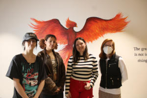 Discovery High students (left to right) Madison Dulong, Audrey Miller-Drapeau, Sophie Knight and Matayah Mach gather near a mural of their school’s mascot, the phoenix, Monday, March 25, 2024. (Kelly Moyer/Post-Record)