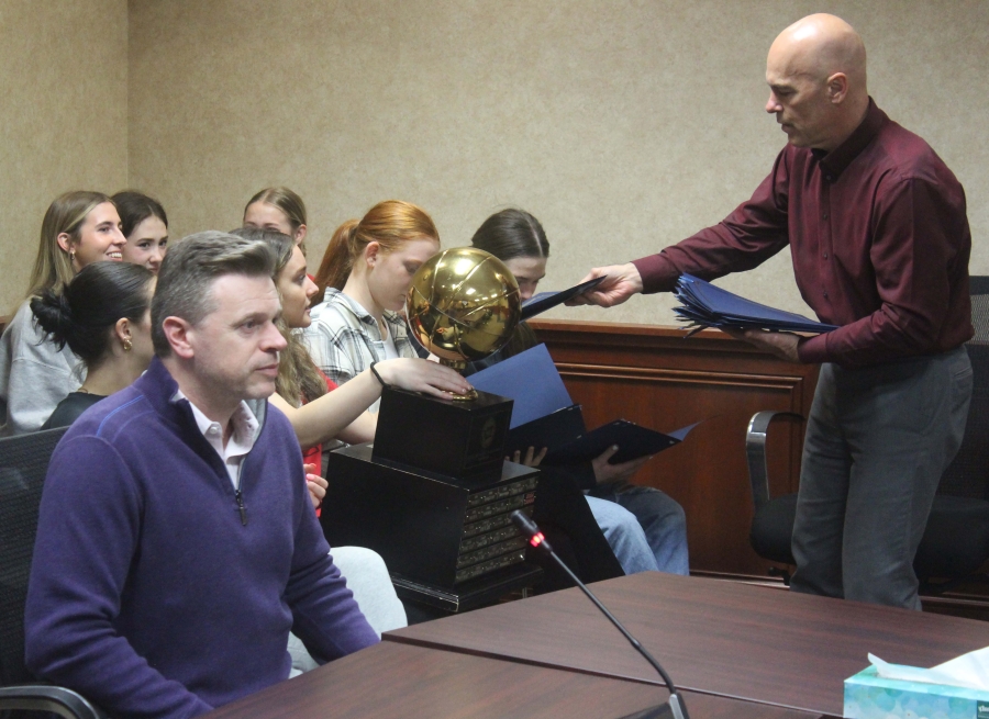 Camas City Administrator Doug Quinn (right) gives copies of a City proclamation to Camas High School girls basketball players while the Papermakers’ coach, Scott Thompson, (left) listens to Camas Mayor Steve Hogan during a Camas City Council meeting, Monday, April 15, 2024.