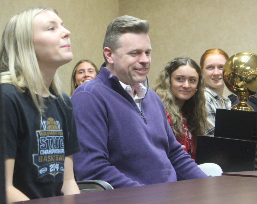 Camas High School girls basketball coach Steve Thompson (center) listens to senior guard Riley Sanz (left) speak during a Camas City Council meeting, Monday, April 15.