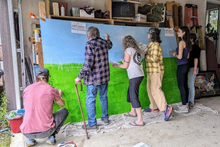Washougal residents transfer the outline of a mural design to a dibond, which will be mounted to three sides of the Hamllik Park bathroom building on April 28, 2024.