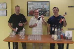 Rediviva Distilling maintenance technician Paul Clark (left), owner Gary Phillips (center) and lead distiller Daniel Ruiz hold bottles of the Washougal distillery’s spirits, July 11, 2024. (Photos by Doug Flanagan/Post-Record)