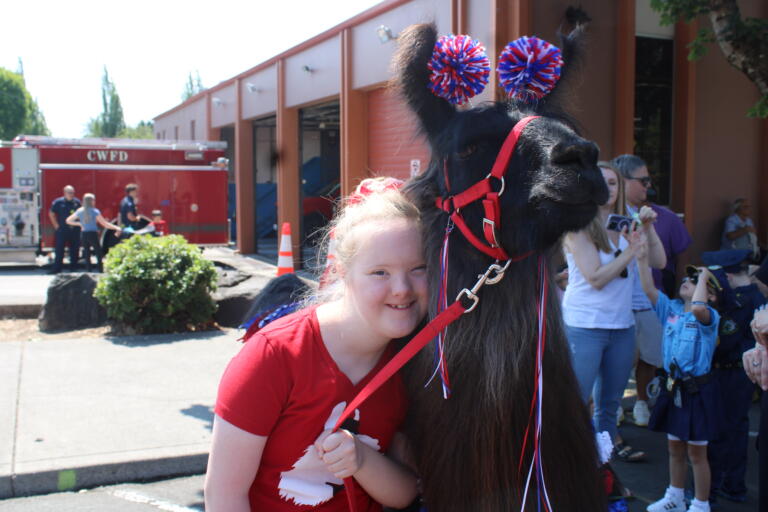 Claire G. hugs Beni, a therapy llama at Mountain Peaks Therapy Llamas and Alpacas, during the first day of the 2024 Camas Days festival in downtown Camas, Friday, July 26, 2024. (Kelly Moyer/Post-Record)
