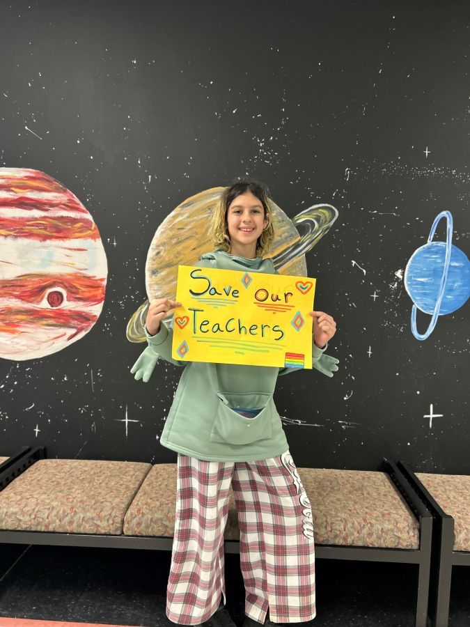 Odyssey Middle School student Kat Basse holds a "Save Our Teachers" sign inside the Camas middle school Wednesday morning, Feb. 26, 2025, during a student protest of a Camas School District budget reduction plan to move Odyssey students into the nearby Discovery High School in the fall.