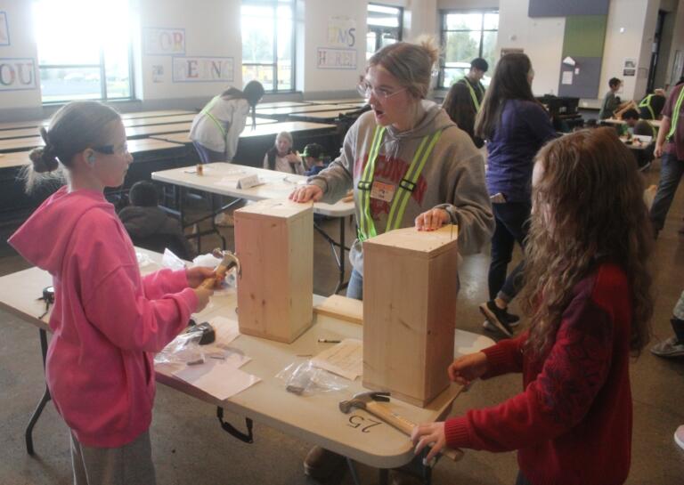 Washougal High School student Lilly Throop, center, helps Columbia River Gorge Elementary School students Peri Fick, left, and Aedan McCauley, right, build toolboxes Feb. 25.