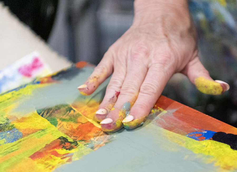 Artist Heidi Curley smudges paint around with her fingers at her art studio in Camas Feb. 25, 2025. Curley says she finds painting with her hands “messy, but freeing.”