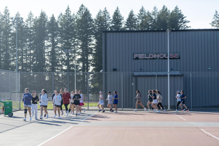 The Camas girls tennis team jogs around the courts Friday at Camas High School.