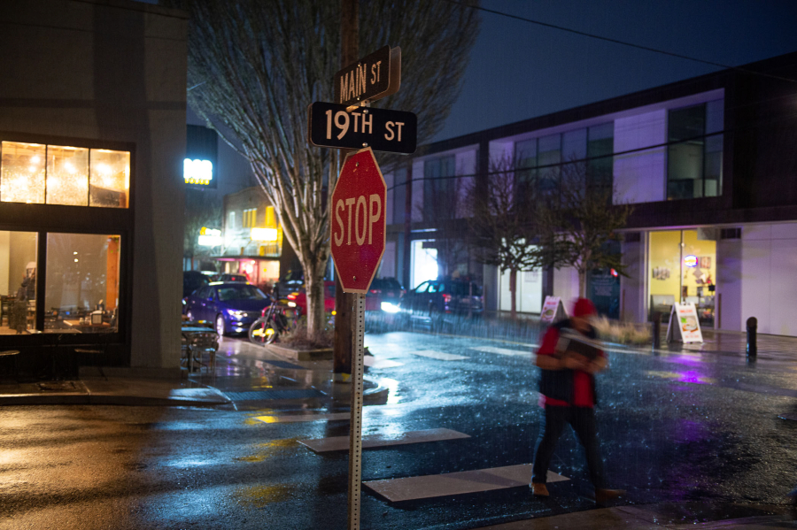 A pedestrian crosses a darkened crosswalk at the corner of 19th and Main streets in Washougal. City Councilor Molly Coston is advocating for the City of Washougal to upgrade the lighting and brighten a dark downtown. (James Rexroad/for The Columbian)